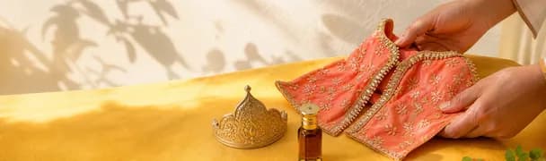 Brass puja vessels and an attar bottle laid out on a saffron cloth